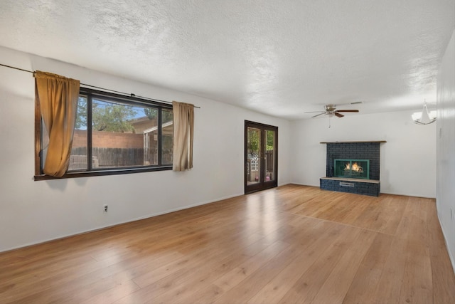 9200 Lagrima De Oro Rd NE, Albuquerque, NM 87111 - unfurnished living room with wood finished floors, healthy amount of natural light, a ceiling fan, a textured ceiling, and a brick fireplace