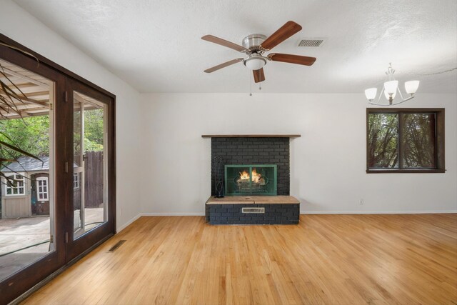 9200 Lagrima De Oro Rd NE, Albuquerque, NM 87111 - unfurnished living room featuring wood finished floors, a chandelier, a brick fireplace, and a ceiling fan