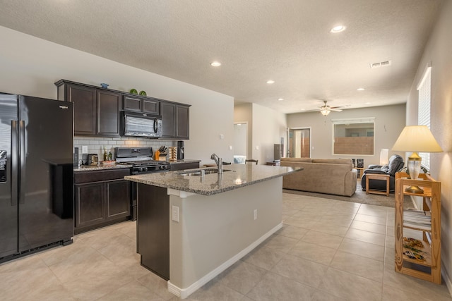 4880 Blackburn Rd, Rio Rancho, NM 87144 - kitchen featuring black appliances, light stone countertops, light tile patterned floors, an island with sink, and tasteful backsplash