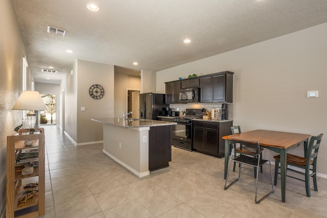 4880 Blackburn Rd, Rio Rancho, NM 87144 - kitchen with black appliances, a center island with sink, light stone countertops, tasteful backsplash, and a textured ceiling