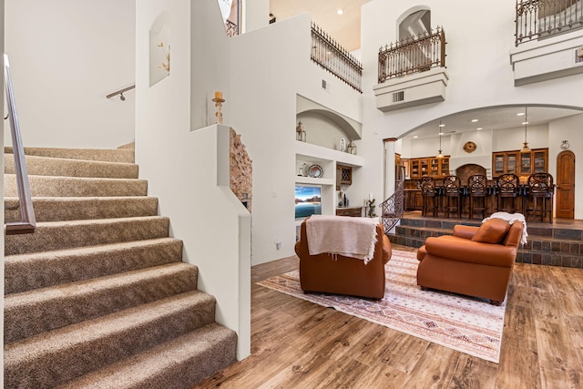 746 Chamisal Rd NW, Los Ranchos, NM 87107 - living area with arched walkways, a high ceiling, wood finished floors, stairs, and built in features