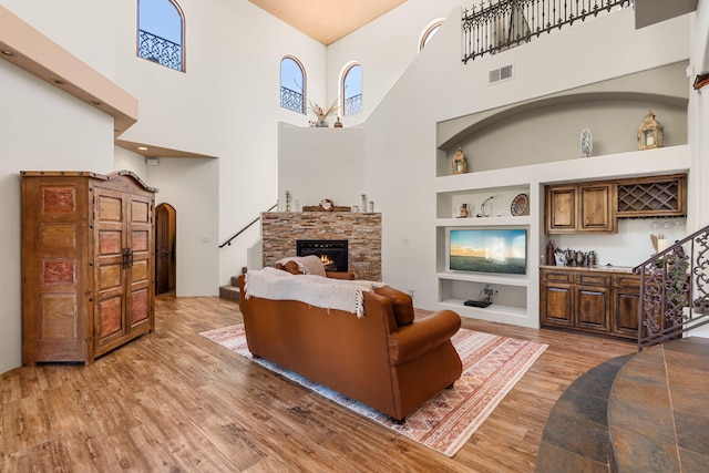 746 Chamisal Rd NW, Los Ranchos, NM 87107 - living area featuring built in features, light wood-style floors, a towering ceiling, a stone fireplace, and stairway