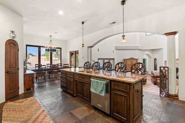 746 Chamisal Rd NW, Los Ranchos, NM 87107 - kitchen with stainless steel dishwasher, stone tile flooring, arched walkways, a textured ceiling, and a kitchen island with sink