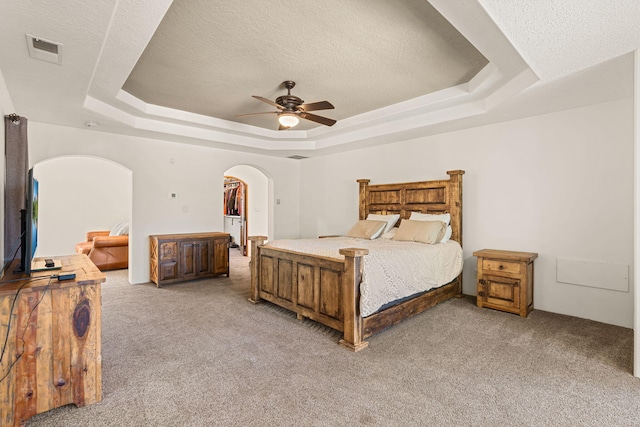 746 Chamisal Rd NW, Los Ranchos, NM 87107 - bedroom featuring a raised ceiling, arched walkways, light carpet, a textured ceiling, and a ceiling fan