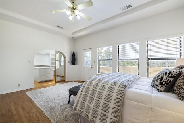 8712 Greenarbor Rd NE, Albuquerque, NM 87122 - bedroom featuring light wood finished floors, a raised ceiling, access to exterior, arched walkways, and a ceiling fan