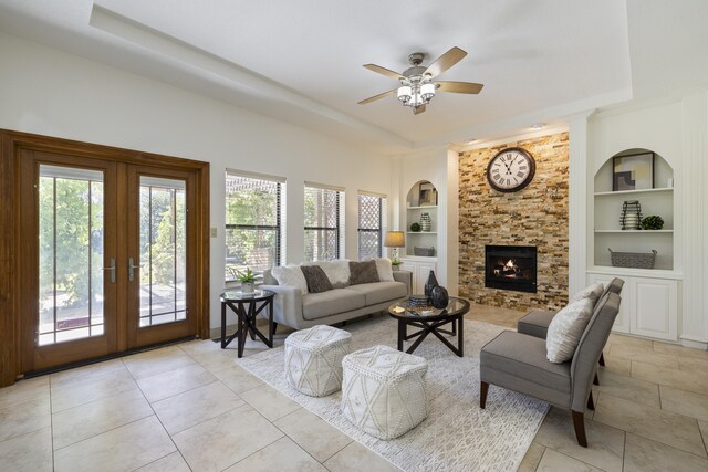 8712 Greenarbor Rd NE, Albuquerque, NM 87122 - living area featuring built in features, french doors, a tray ceiling, a ceiling fan, and a stone fireplace