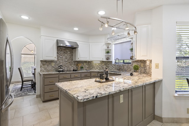 8712 Greenarbor Rd NE, Albuquerque, NM 87122 - kitchen with open shelves, wall chimney range hood, gray cabinets, freestanding refrigerator, and decorative backsplash