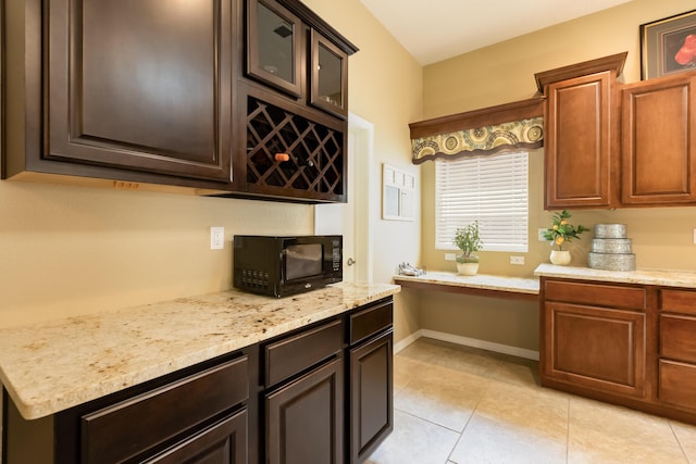 4601 Mi Cordelia Dr NW, Albuquerque, NM 87120 - kitchen featuring black microwave, light stone countertops, light tile patterned floors, glass insert cabinets, and dark brown cabinets