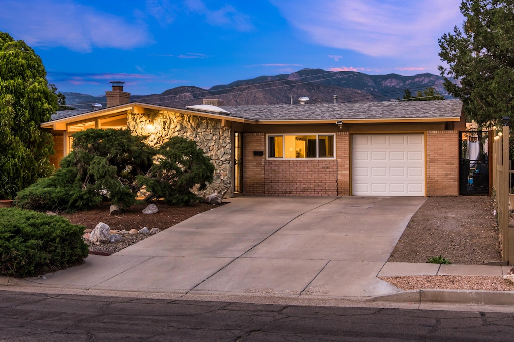 1608 Boatright Dr NE, Albuquerque, NM 87112 - ranch-style home featuring a garage, a mountain view, concrete driveway, and brick siding