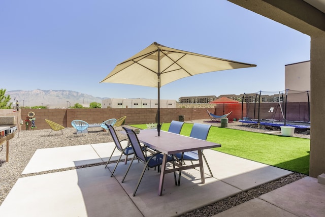 4381 Lauren Loop NE, Rio Rancho, NM 87124 - fenced backyard featuring a trampoline, outdoor dining area, a patio area, and a mountain view