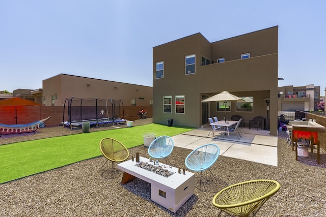 4381 Lauren Loop NE, Rio Rancho, NM 87124 - back of property featuring a trampoline, a patio, and stucco siding