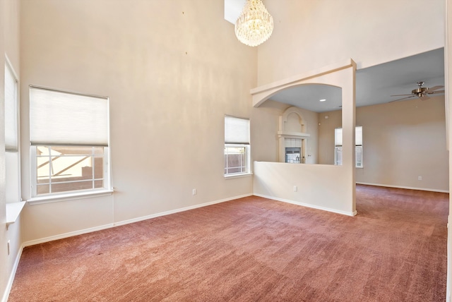10431 Crosscut Dr NW, Albuquerque, NM 87114 - unfurnished living room featuring a towering ceiling, carpet, a chandelier, a glass covered fireplace, and ceiling fan