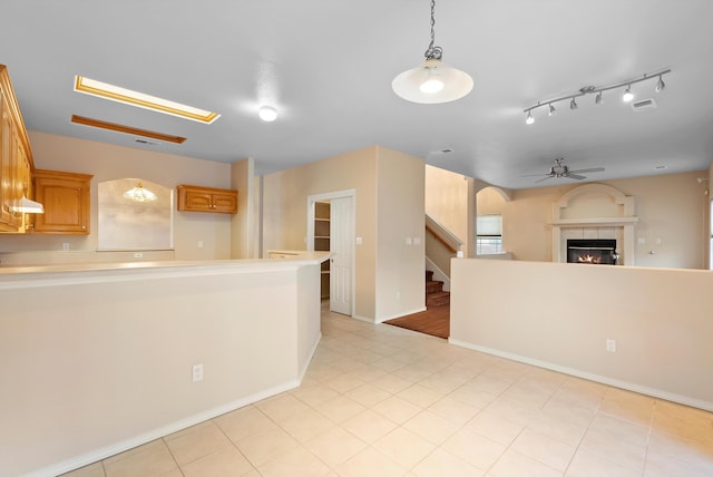10431 Crosscut Dr NW, Albuquerque, NM 87114 - kitchen featuring a ceiling fan, a tiled fireplace, light countertops, open floor plan, and a peninsula