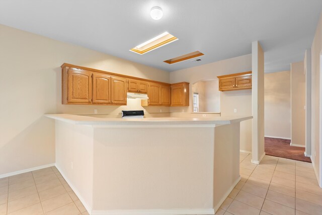 10431 Crosscut Dr NW, Albuquerque, NM 87114 - kitchen featuring under cabinet range hood, light countertops, light tile patterned flooring, and a peninsula