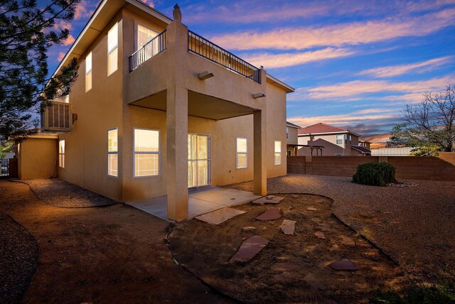 10431 Crosscut Dr NW, Albuquerque, NM 87114 - back of property at dusk featuring stucco siding, a patio area, and a balcony
