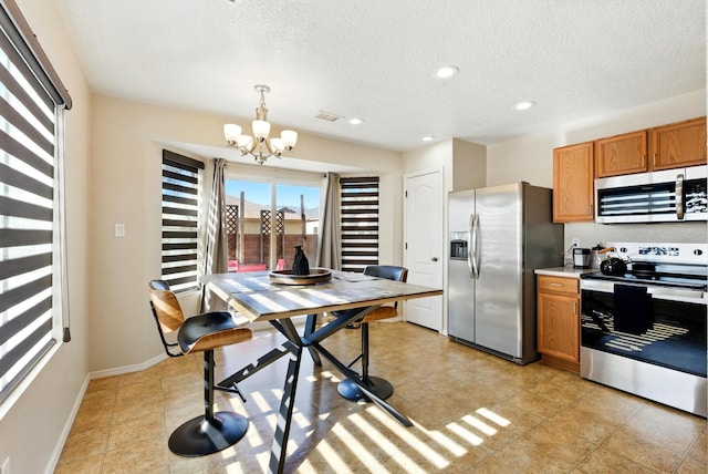 10636 Mcmichael Ln SW, Albuquerque, NM 87121 - kitchen with stainless steel appliances, a chandelier, brown cabinets, a textured ceiling, and pendant lighting