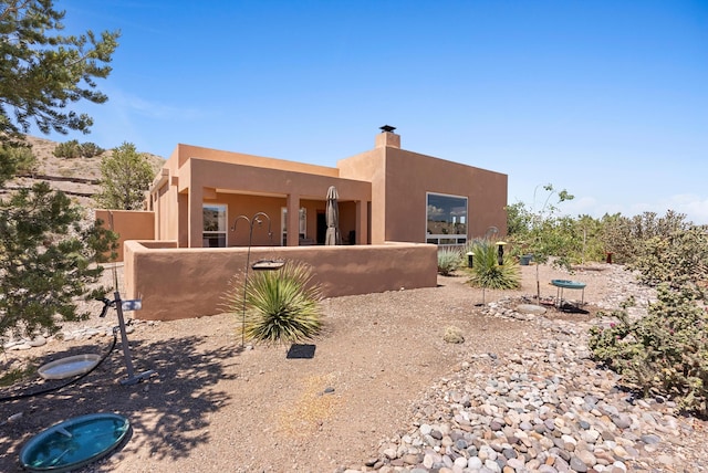 3 Seasons Cir, Placitas, NM 87043 - back of house with a fenced front yard, stucco siding, and a chimney