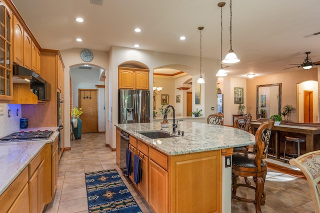 924 Seattle Slew Ave SE, Albuquerque, NM 87112 - kitchen with arched walkways, appliances with stainless steel finishes, an island with sink, a breakfast bar area, and light stone counters