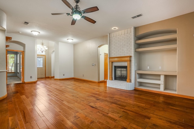 924 Seattle Slew Ave SE, Albuquerque, NM 87112 - unfurnished living room featuring arched walkways, ceiling fan, hardwood / wood-style flooring, and a brick fireplace