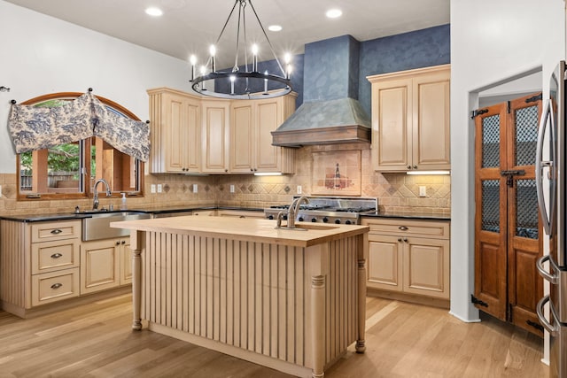 9005 4th St NW, Albuquerque, NM 87114 - kitchen with custom range hood, wood counters, light wood-style floors, a kitchen island with sink, and cream cabinetry