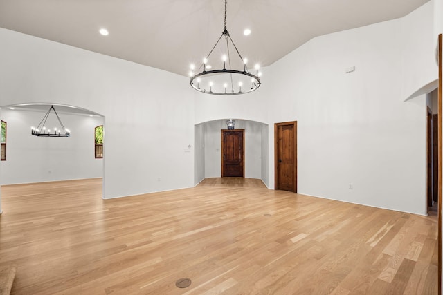 9005 4th St NW, Albuquerque, NM 87114 - unfurnished room featuring arched walkways, a chandelier, light wood-style flooring, and high vaulted ceiling