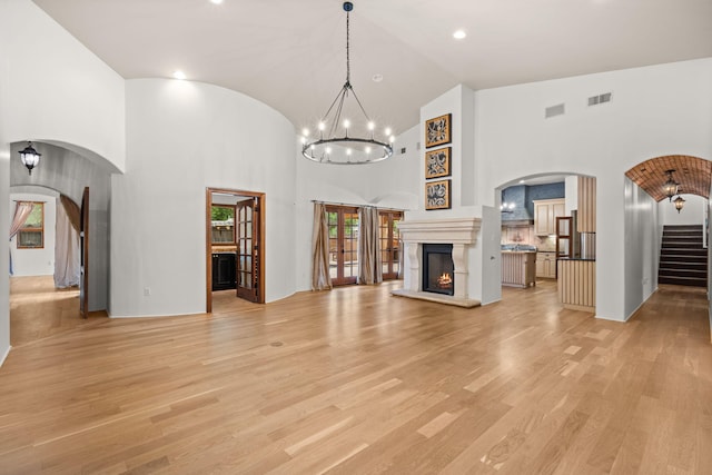 9005 4th St NW, Albuquerque, NM 87114 - unfurnished living room featuring stairs, light wood-style flooring, a chandelier, high vaulted ceiling, and arched walkways