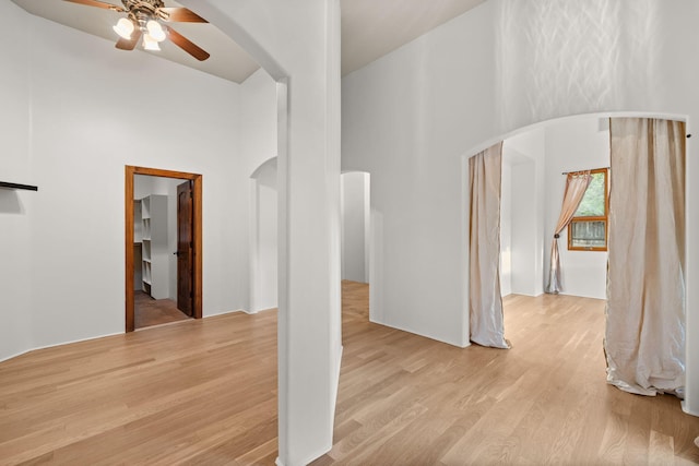 9005 4th St NW, Albuquerque, NM 87114 - unfurnished living room featuring a towering ceiling, arched walkways, ceiling fan, and light wood finished floors