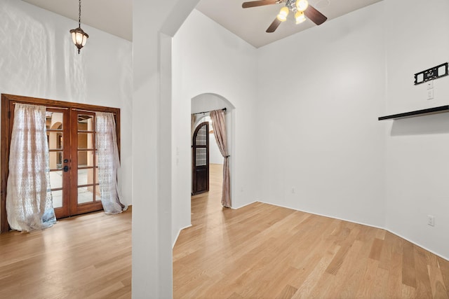 9005 4th St NW, Albuquerque, NM 87114 - spare room featuring arched walkways, french doors, light wood-type flooring, ceiling fan, and a towering ceiling