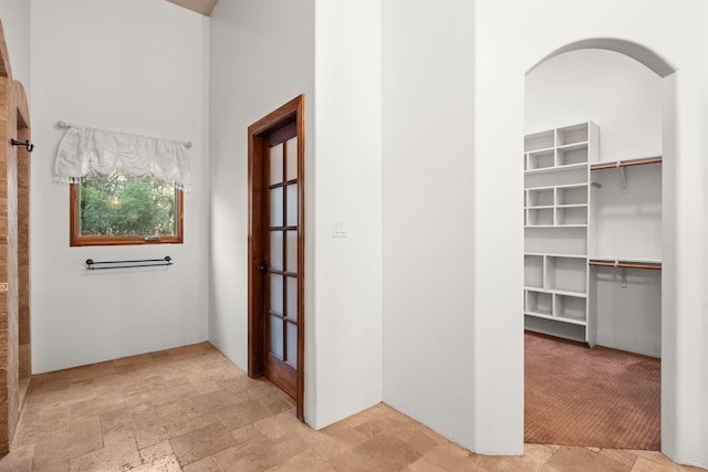 9005 4th St NW, Albuquerque, NM 87114 - corridor featuring light stone finish floors, a towering ceiling, and arched walkways