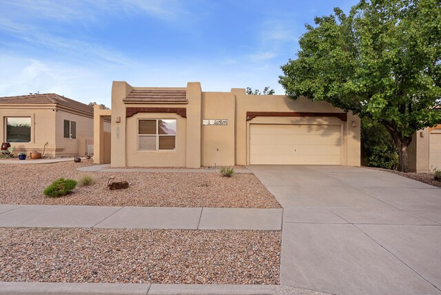 3912 Tundra Swan Ct NW, Albuquerque, NM 87120 - pueblo-style house with a garage, concrete driveway, and stucco siding