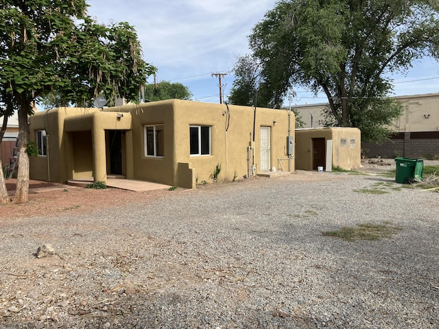 3107 Draxton Ave SW, Albuquerque, NM 87105 - view of front of property with stucco siding, gravel driveway, and a storage shed