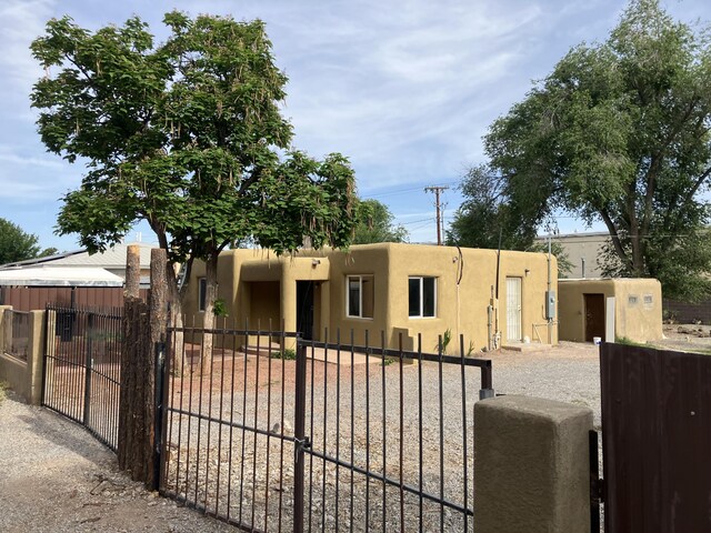 3107 Draxton Ave SW, Albuquerque, NM 87105 - pueblo revival-style home featuring a fenced front yard, stucco siding, and a gate