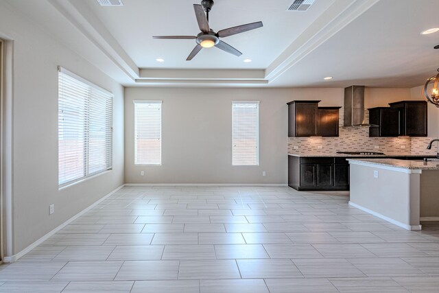 4289 Crowned Eagle Loop NE, Rio Rancho, NM 87144 - kitchen featuring wall chimney exhaust hood, ceiling fan, backsplash, gas stovetop, and a raised ceiling