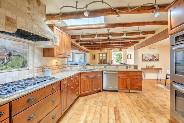 78 Quirks Ln, Corrales, NM 87048 - kitchen with appliances with stainless steel finishes, a peninsula, brown cabinets, tasteful backsplash, and beam ceiling