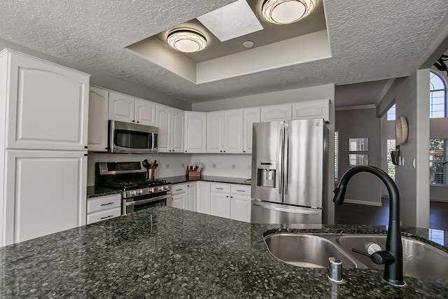 6109 Chamblee Ct NE, Albuquerque, NM 87111 - kitchen with stainless steel appliances, a textured ceiling, a tray ceiling, dark stone countertops, and white cabinets
