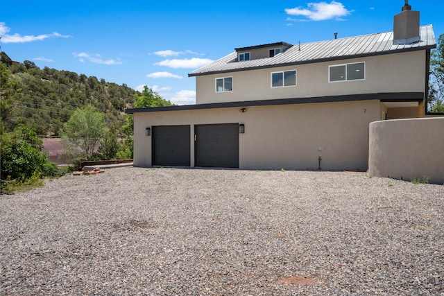 7 Corte De Canoncito, Cedar Crest, NM 87008 - back of property featuring stucco siding, gravel driveway, a chimney, and a metal roof