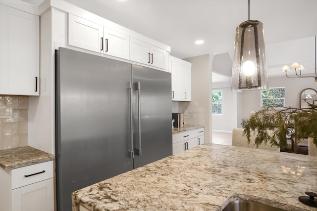 7 Corte De Canoncito, Cedar Crest, NM 87008 - kitchen with built in fridge, tasteful backsplash, white cabinets, light stone countertops, and decorative light fixtures