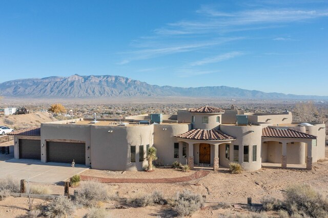 3 Quiet Ln, Corrales, NM 87048 - view of front facade featuring an attached garage, concrete driveway, stucco siding, and a mountain view