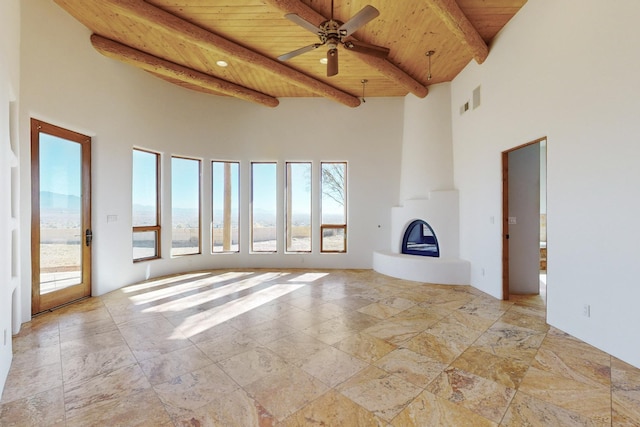 3 Quiet Ln, Corrales, NM 87048 - unfurnished living room with a wooden ceiling with exposed beams, a high ceiling, plenty of natural light, a fireplace, and a ceiling fan