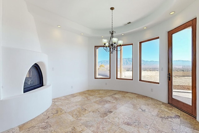 3 Quiet Ln, Corrales, NM 87048 - unfurnished living room with recessed lighting, healthy amount of natural light, a chandelier, stone finish flooring, and a large fireplace