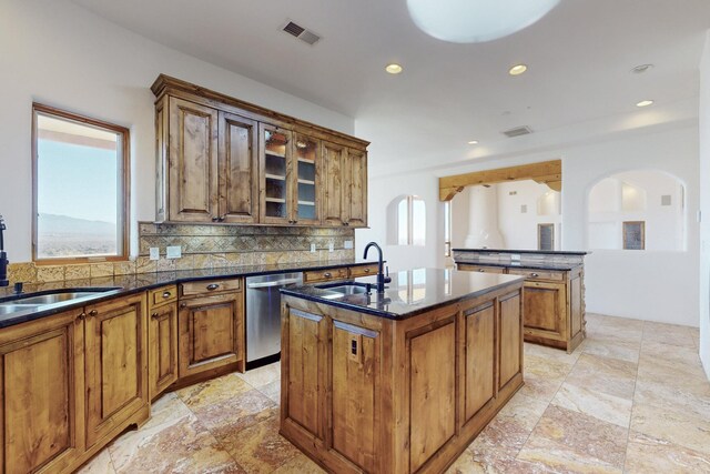 3 Quiet Ln, Corrales, NM 87048 - kitchen featuring stainless steel dishwasher, an island with sink, arched walkways, brown cabinetry, and decorative backsplash