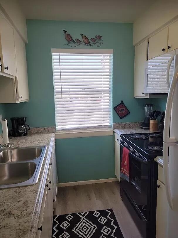 4601 Carlisle Blvd NE Unit H-2, Albuquerque, NM 87109 - kitchen with white appliances, light wood-style floors, white cabinetry, and light countertops