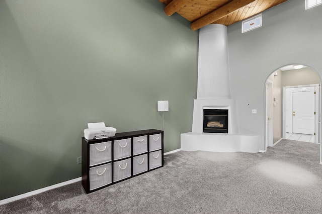 6021 Alamosa Way NW, Albuquerque, NM 87107 - unfurnished living room with a wood ceiling with exposed beams, carpet, arched walkways, and a large fireplace