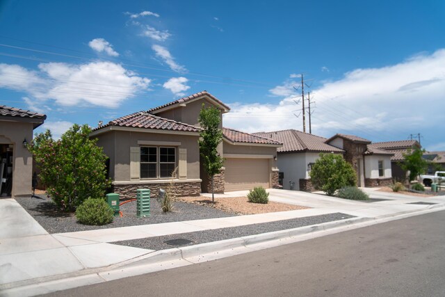 6873 Cleary Loop NE, Rio Rancho, NM 87144 - mediterranean / spanish home with stucco siding, stone siding, an attached garage, a tiled roof, and concrete driveway