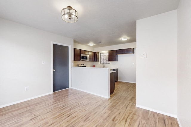 4807 Parsifal St NE, Albuquerque, NM 87111 - kitchen with stainless steel microwave, dark brown cabinetry, light wood-style floors, a peninsula, and light countertops