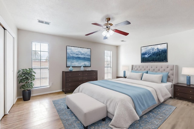 4807 Parsifal St NE, Albuquerque, NM 87111 - bedroom with light wood-type flooring, multiple windows, a textured ceiling, ceiling fan, and a closet