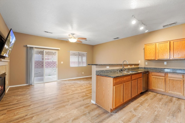 5443 Reserve Ct NE, Rio Rancho, NM 87144 - kitchen featuring stainless steel dishwasher, a ceiling fan, light wood-style flooring, a peninsula, and a glass covered fireplace