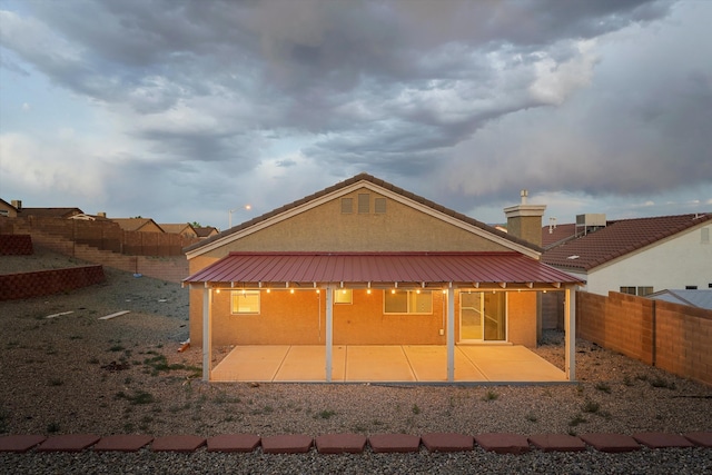5443 Reserve Ct NE, Rio Rancho, NM 87144 - back of property with a patio, a fenced backyard, stucco siding, a metal roof, and a chimney