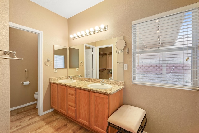5443 Reserve Ct NE, Rio Rancho, NM 87144 - bathroom with wood finished floors, double vanity, a textured wall, and a walk in closet