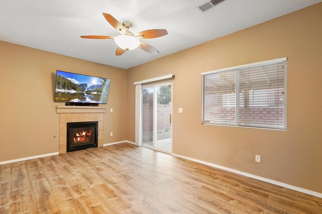 5443 Reserve Ct NE, Rio Rancho, NM 87144 - unfurnished living room with wood finished floors, a tile fireplace, and a ceiling fan